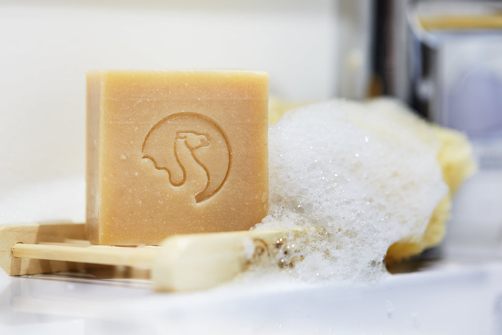 Savon au lait de chamelle de face poser su une table avec de la mousse